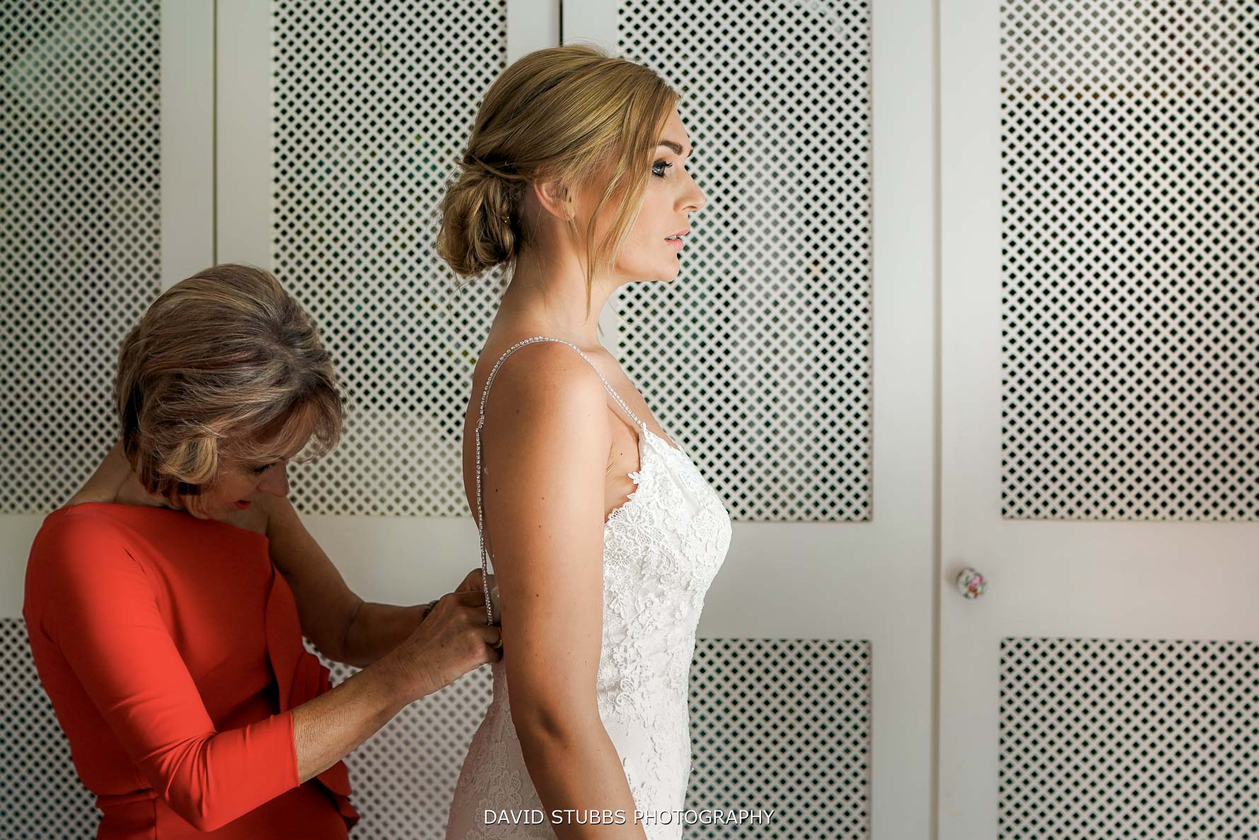 side on composition of bride having her wedding dress put on